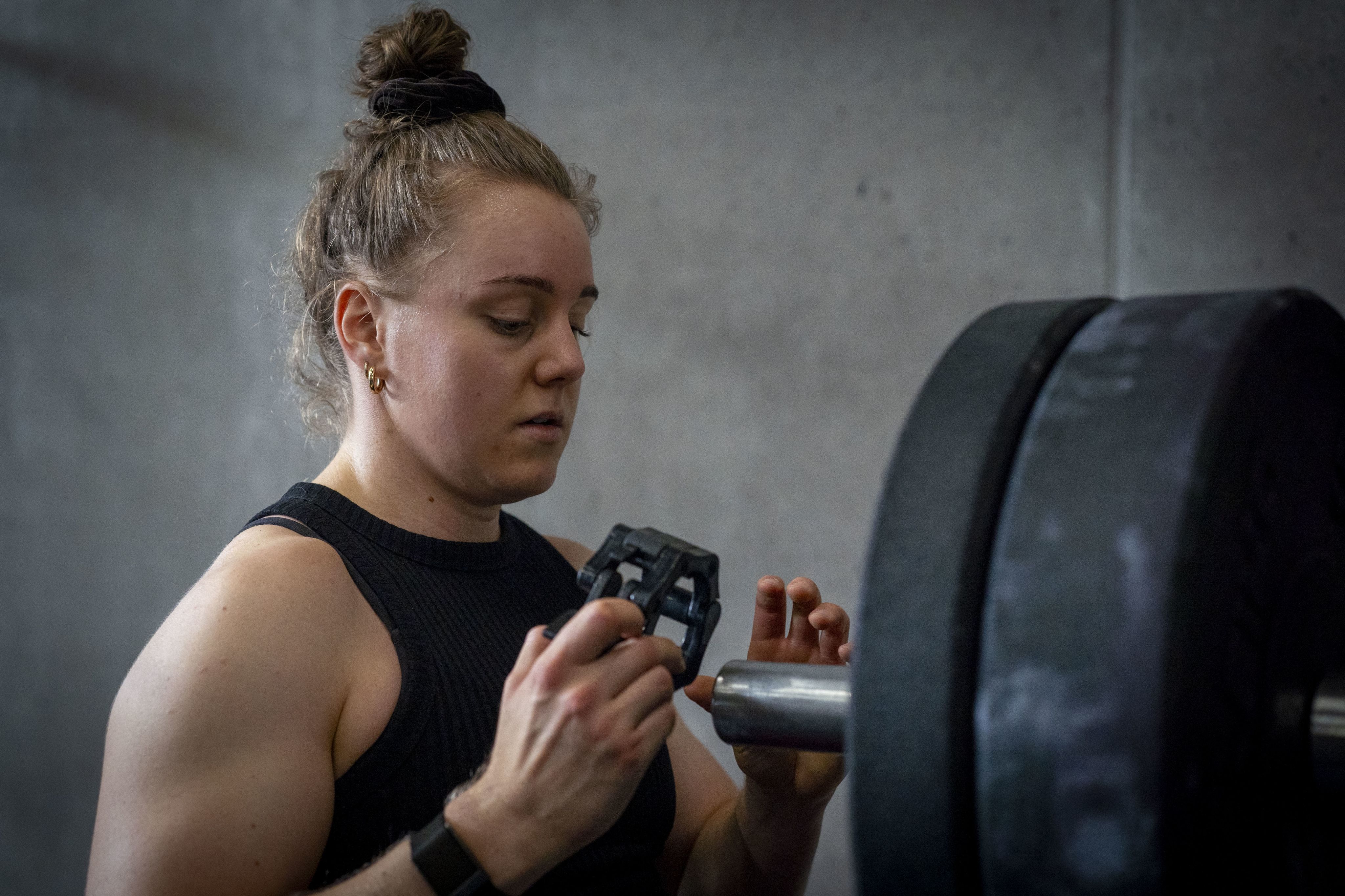 Die Crossfitterin lädt Gewichte auf eine Langhantel
