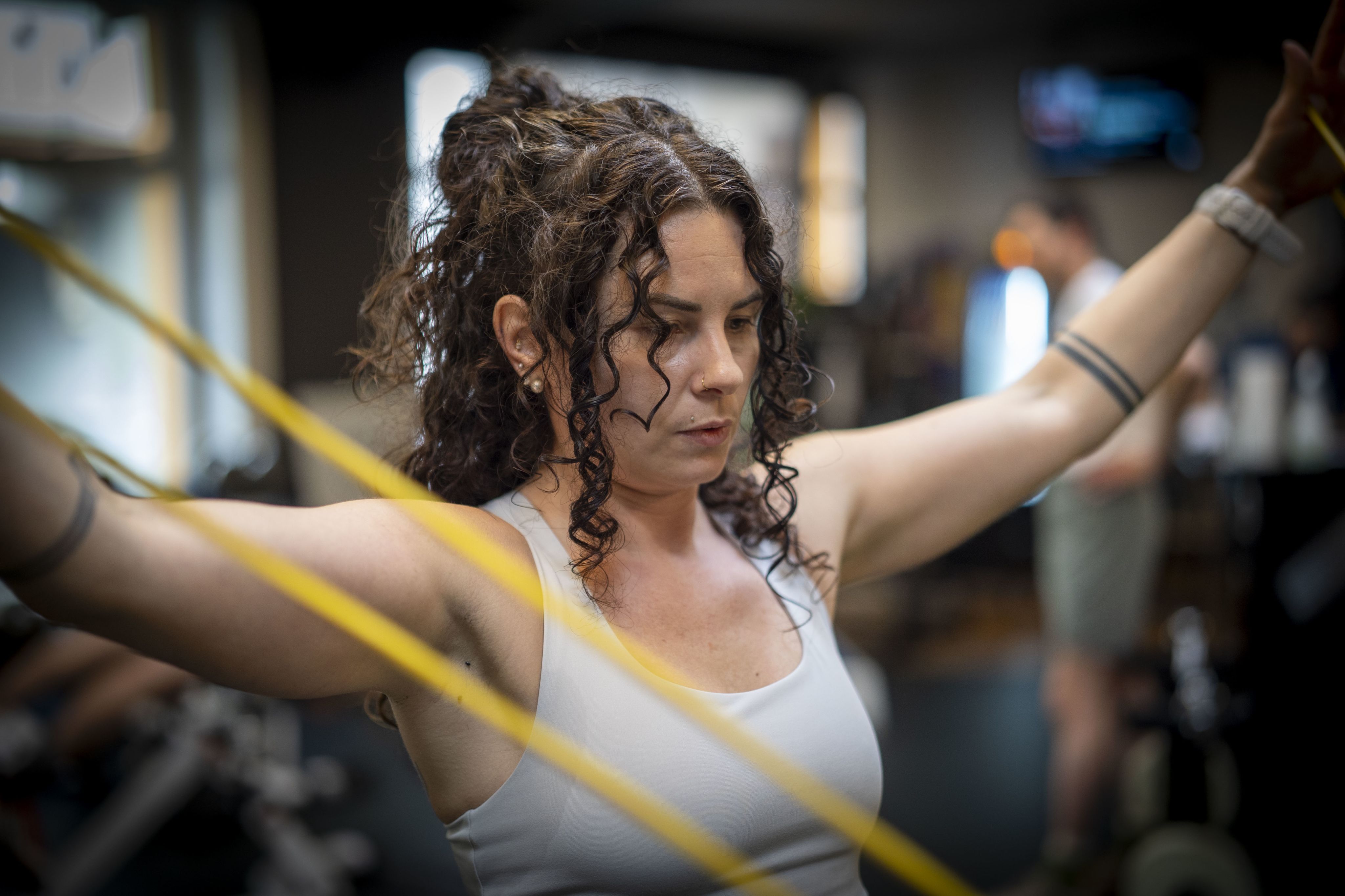 Die Athletin macht eine Armübung mit Gummibändern.
