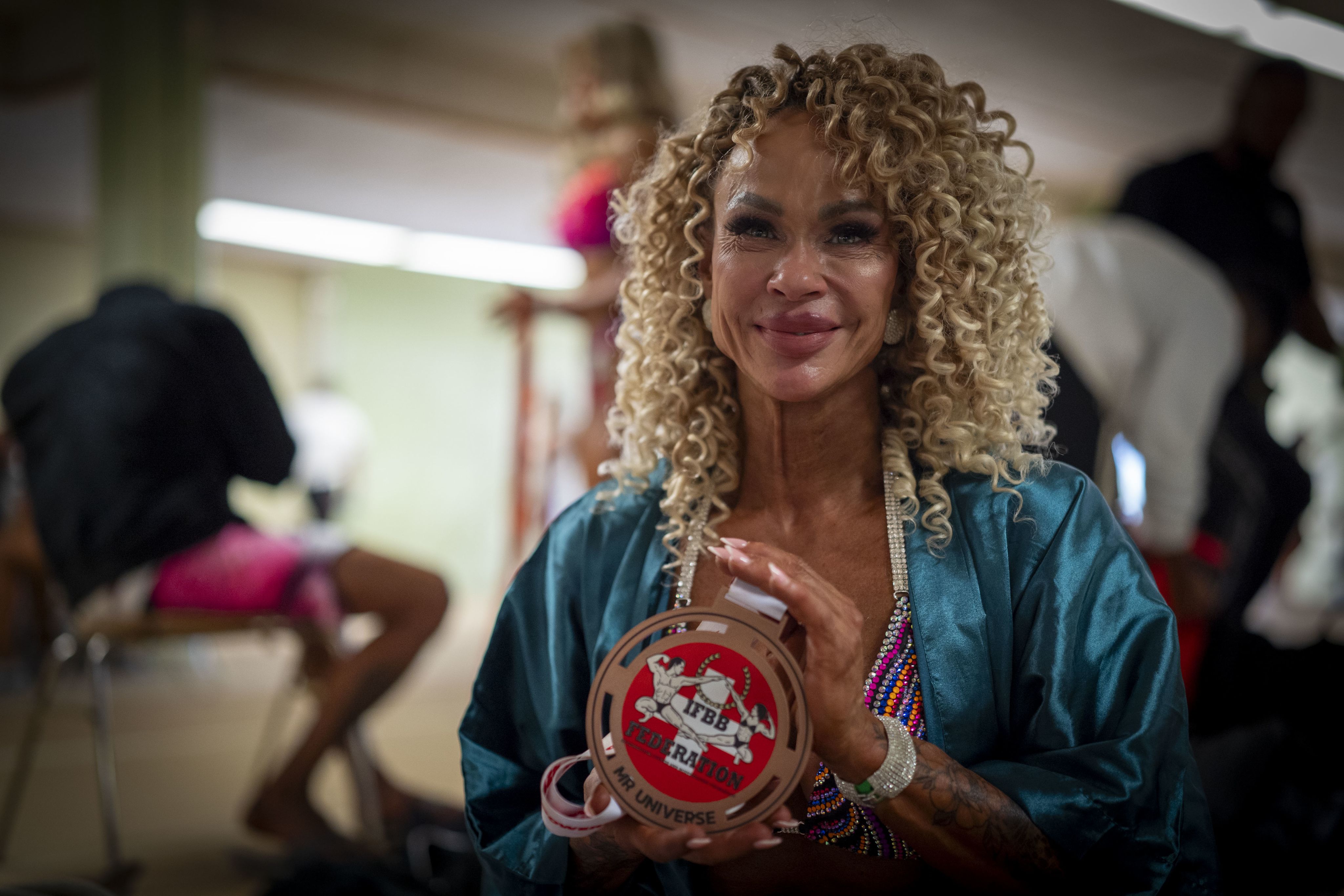 Frau zeigt ihre Medaille von den Mr. Universe Wahlen